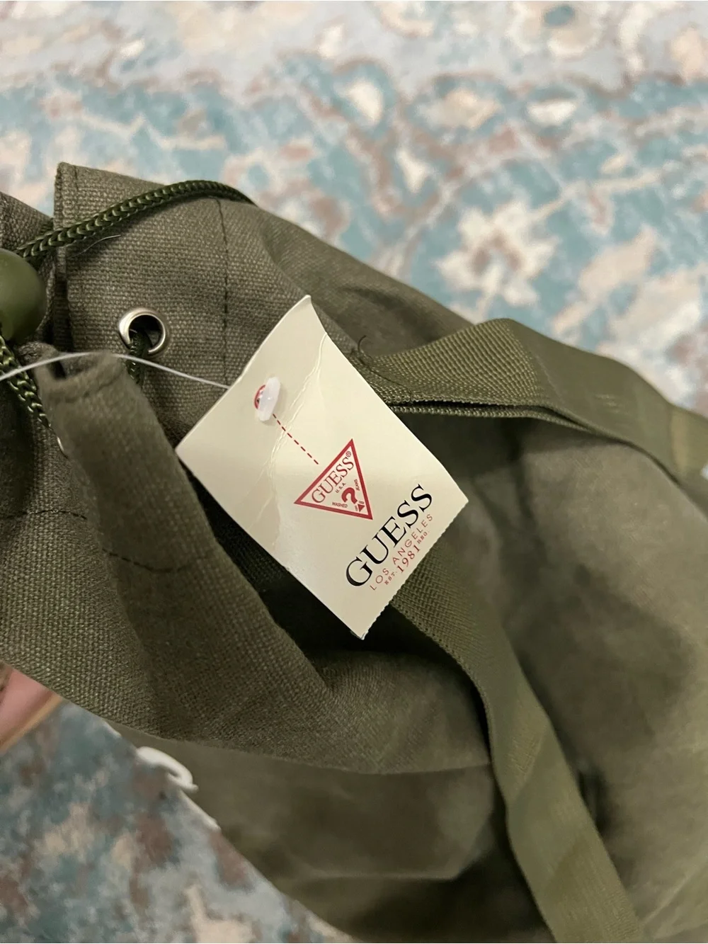 GUESS Olive Canvas Drawstring Sling Duffel Bag with zipper bottom.